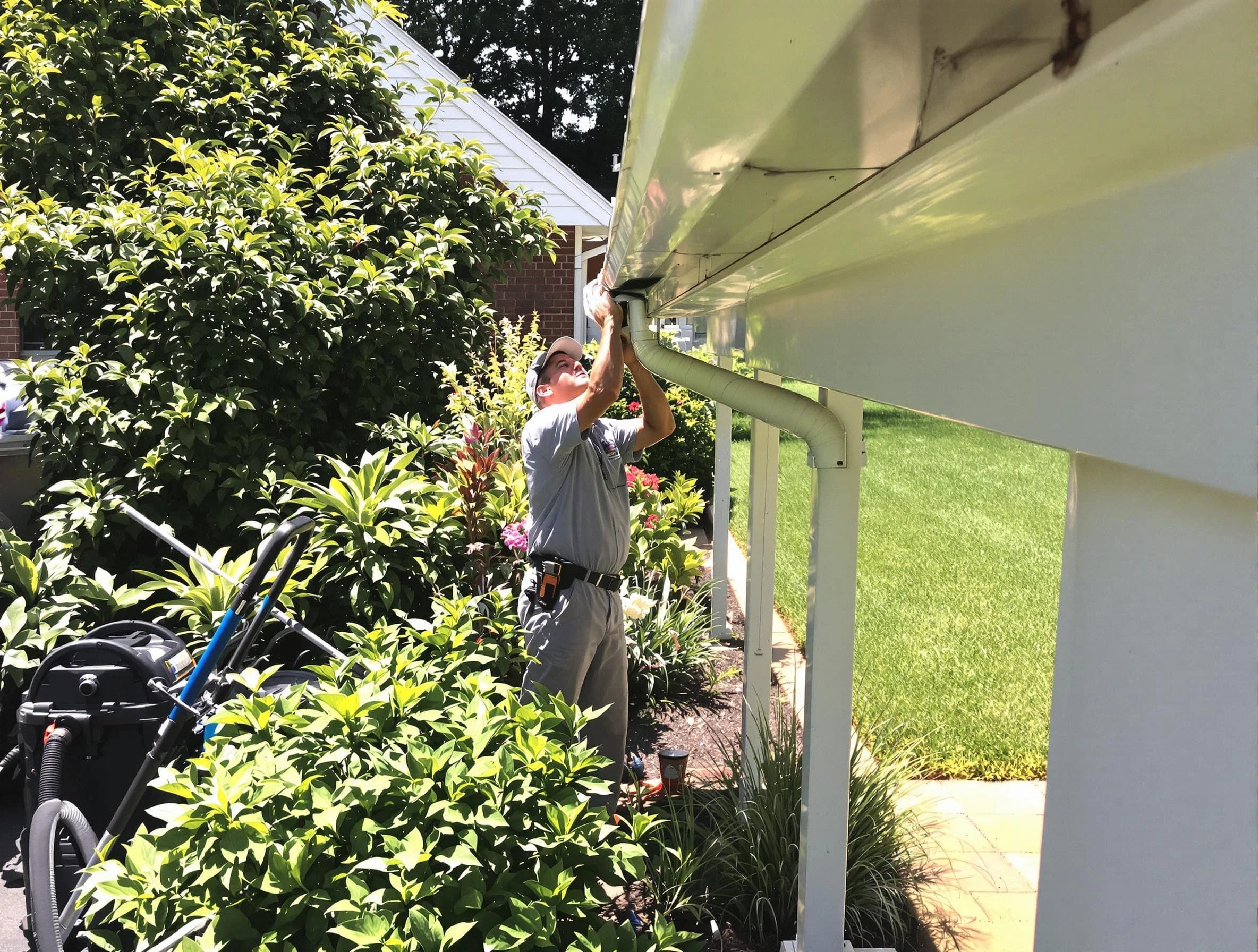 Technician flushing a blockage from a downspout in Bedford, OH